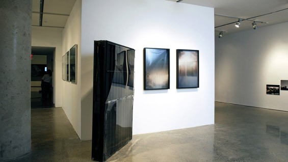 Installation view of Oscar Tuazon’s Black Slab, 2008 (center right) and Afognak (triptych), 2008 (center left)